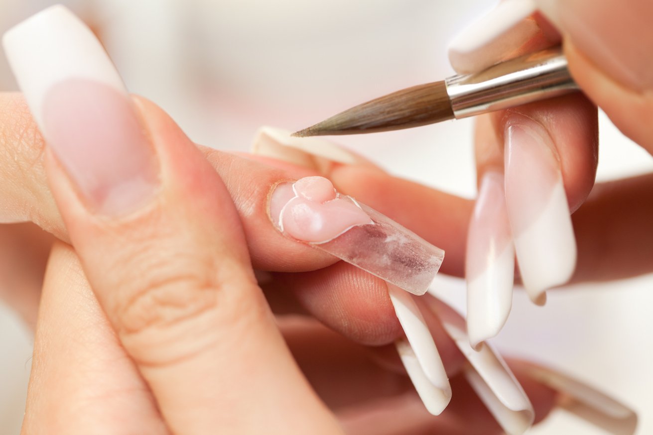 Hands during nail modeling stage of acrylic manicure process